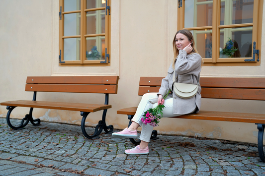 Women sitting on the bench with flowers wearing pink barefoot street shoes.