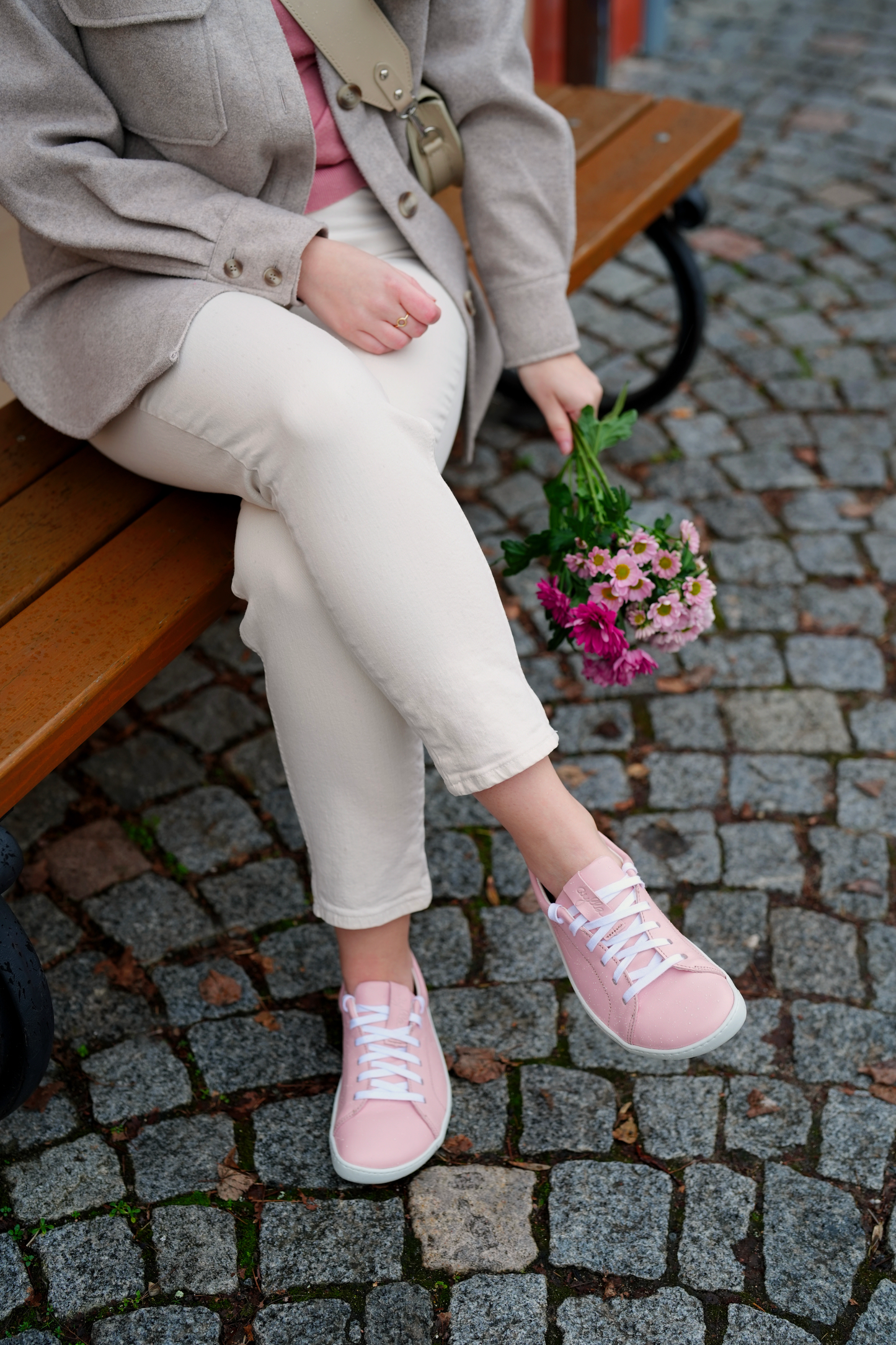 Women sitting on the bench with flowers wearing pink barefoot street shoes.