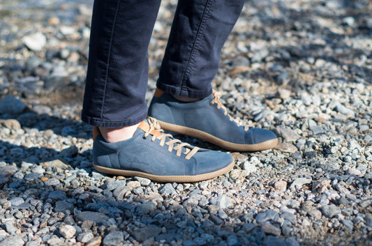 Realistic photo of men wearing blue vegan barefoot shoes on river bank.
