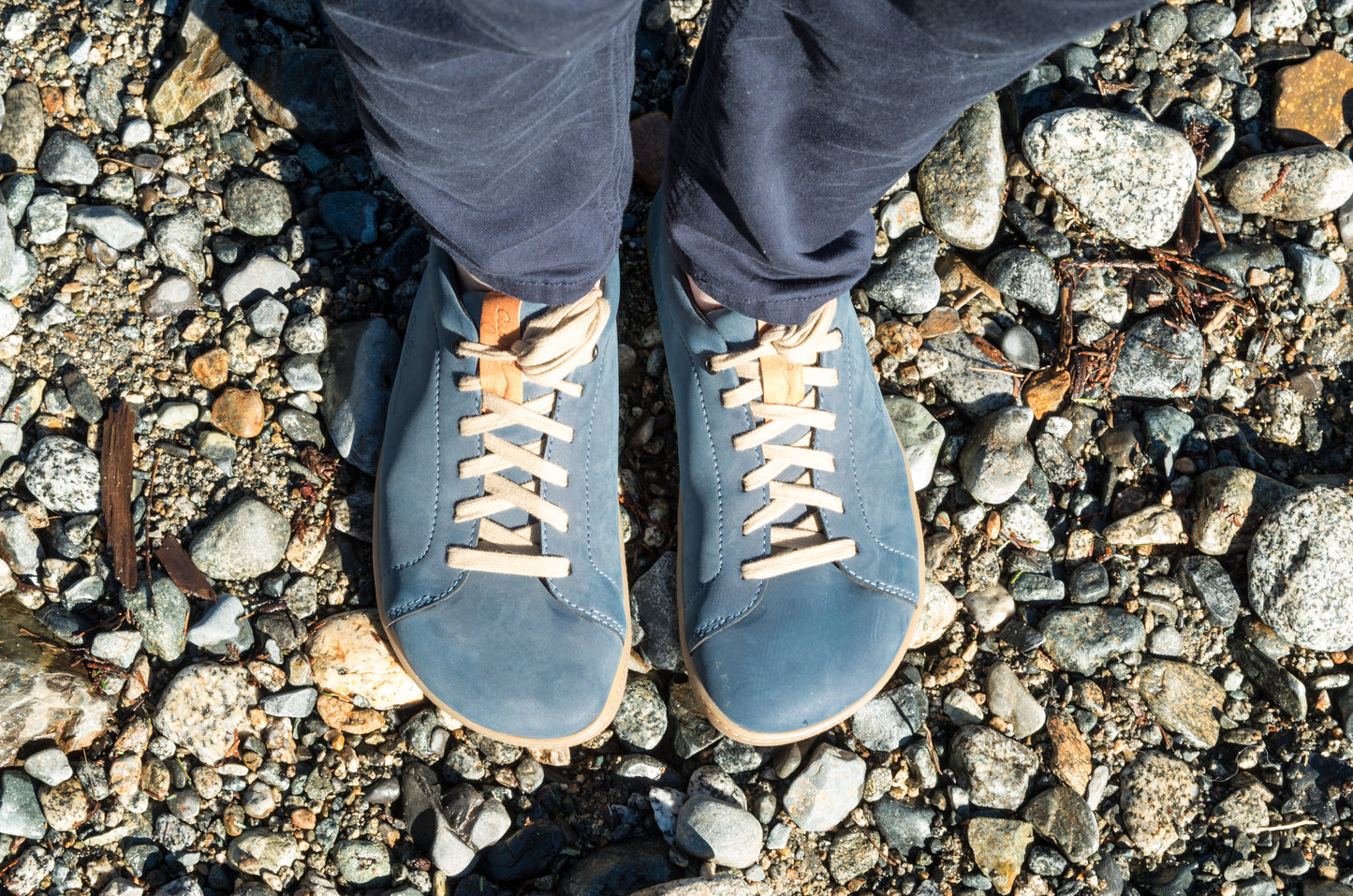 Realistic photo of men wearing blue vegan barefoot shoes on river bank.