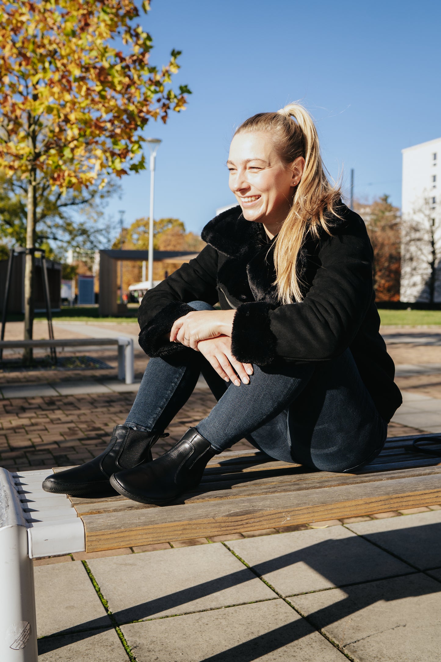 Woman sitting on bench wearing black Chalsea style barefoot shoe
