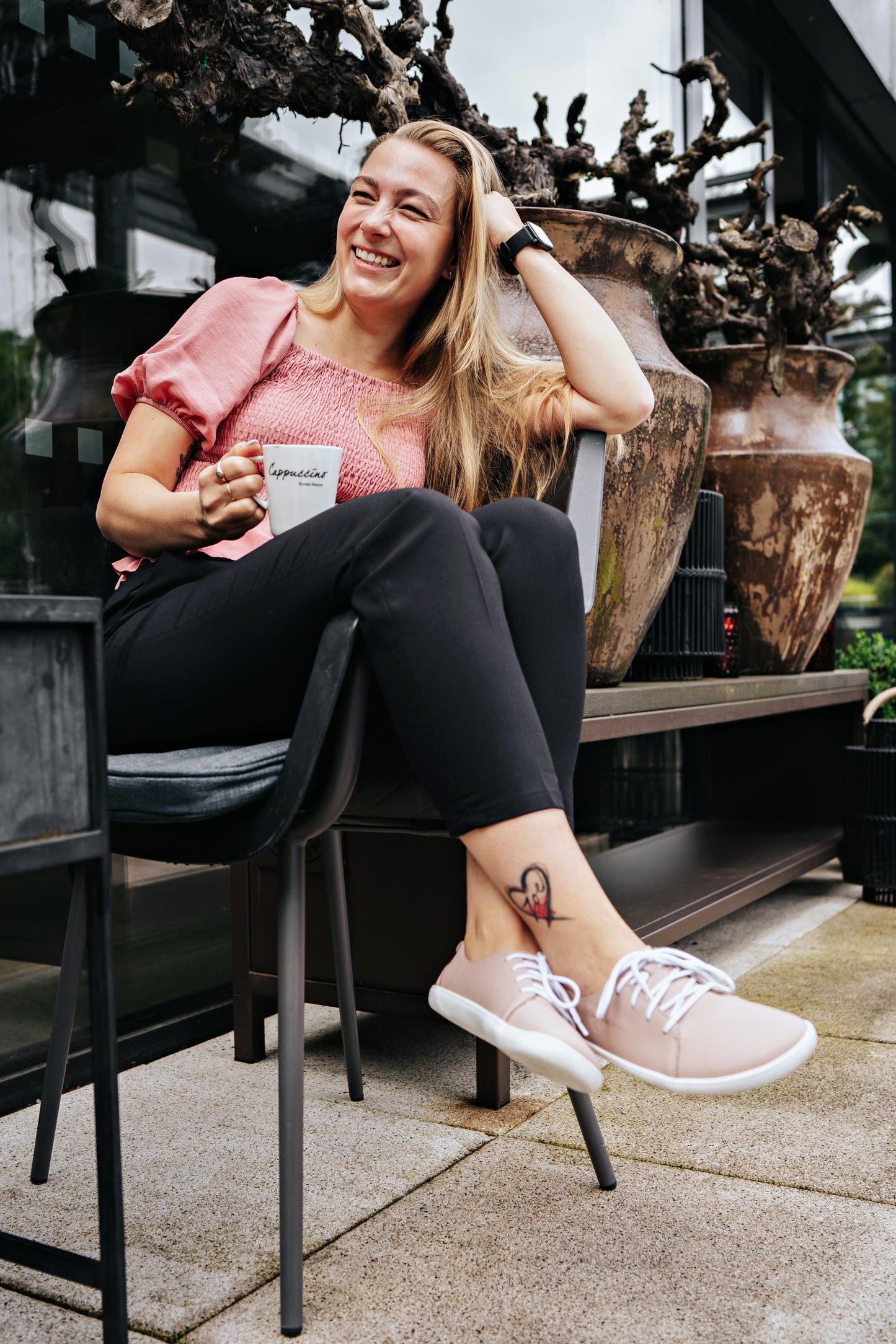 Woman drinking a coffee wearing pink low-cut barefoot shoes