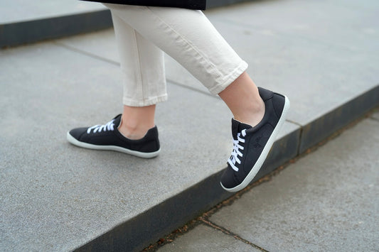 Photo of women walking and wearing vegan barefoot black street shoes. 